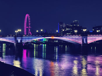 Illuminated bridge over river against sky at night