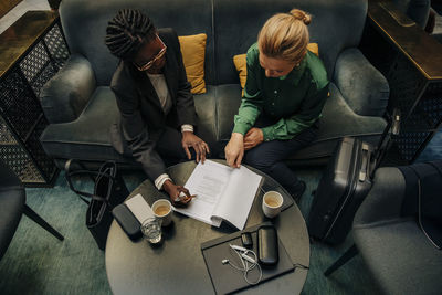 Businesswomen discussing over contract while sitting in hotel lounge