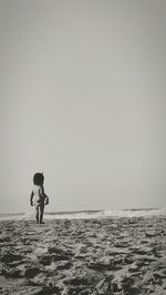 Girl standing at beach against clear sky