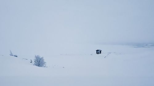 People skiing on snow covered landscape against clear sky