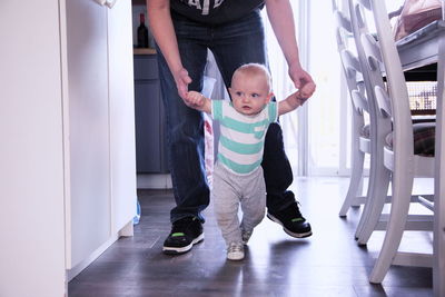 Low section of father and son walking at home