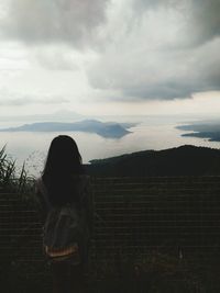 Rear view of woman standing on field against sky