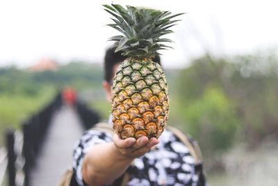 Man holding pineapple while standing outdoors