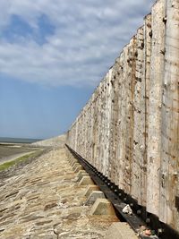 Stone wall by sea against sky