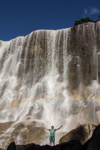 View of man standing in front of waterfall