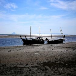 Boat moored on beach against sky