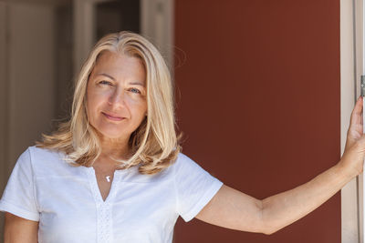 Portrait of smiling woman standing against wall