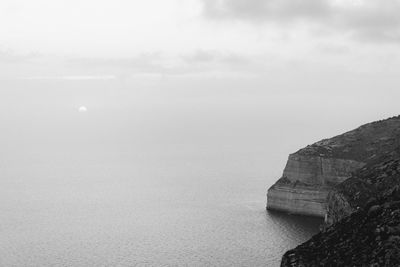 Cliff in sea against sky