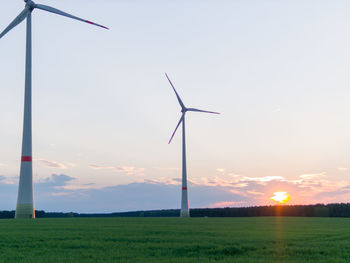 Windmill on field against sky during sunset