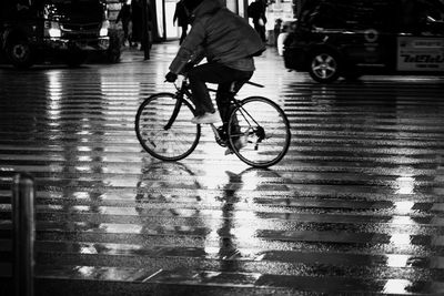 Man riding bicycle on wet street during rainy season