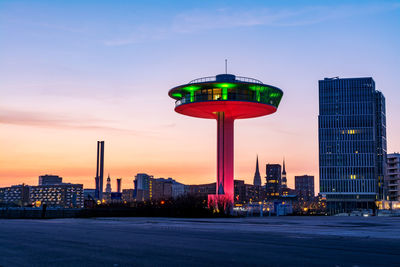 Illuminated buildings in city against sky at dusk