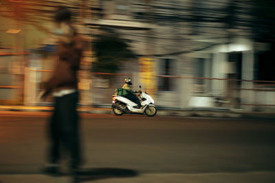 Blurred motion of people riding motorcycle on road