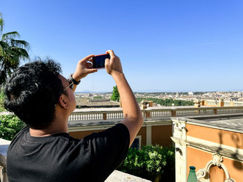 Side view of man photographing through mobile phone