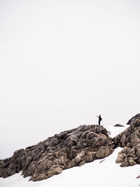 Man on snowcapped mountain against clear sky during winter
