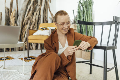 Smiling female entrepreneur using mobile phone at work place