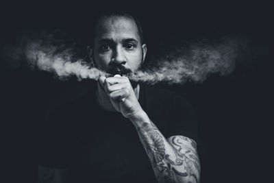 Portrait of man smoking over black background