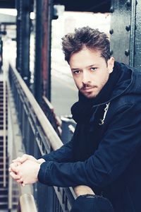 Portrait of young man sitting on railroad track