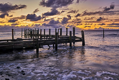 Pier on sea against sky during sunset