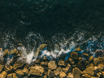 High angle view of sea waves splashing on rocks