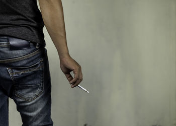Midsection of man holding cigarette