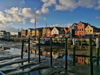 Boats moored in harbor by houses against sky