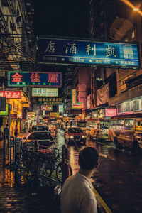 Rear view of man standing on road in city at night