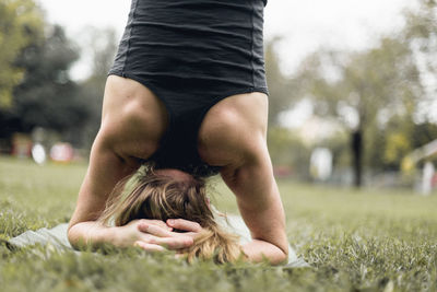 Midsection of young woman on field against sky