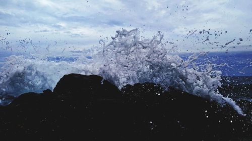 Close-up of waves splashing on sea against sky