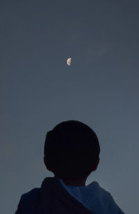 Rear view of silhouette boy against sky at night