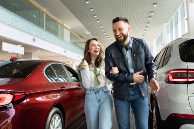 Happy couple walking together in car showroom