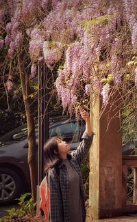 Woman photographing flowers while standing in park