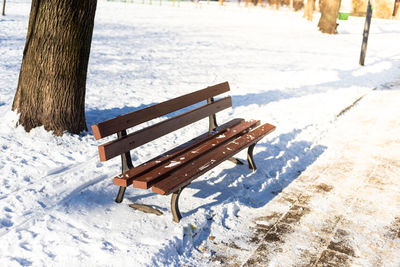 Empty bench in the snow in park