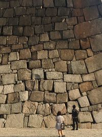 Rear view of people walking on cobblestone