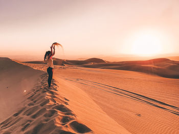 Woman standing on sand dune in desert