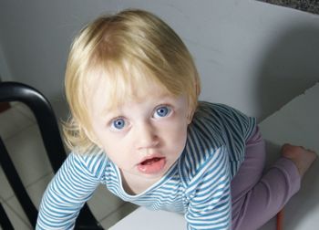 Portrait of cute baby girl kneeling on table at home