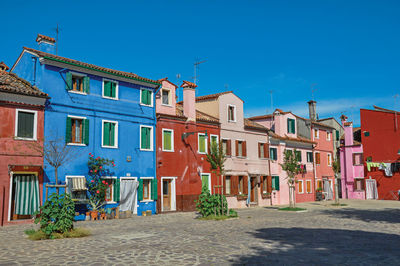 View of colorful houses on sunny day in burano, a gracious little town full of canals in italy.