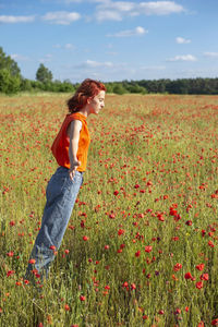 Redhead girl leaning in poppy field