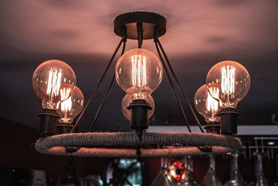 Low angle view of illuminated light bulbs hanging from ceiling