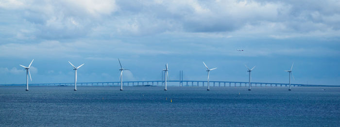 Wind turbines in sea against sky