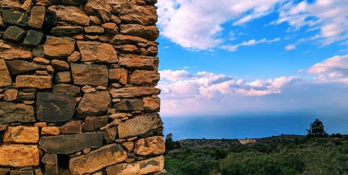 Stone wall by sea against sky