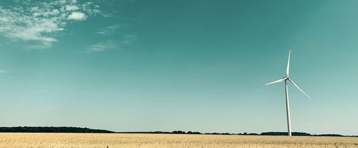 Wind turbines on field against sky