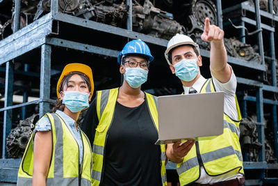 Team engineering three nationality wear face mask uniform working with computer laptop at factory. 