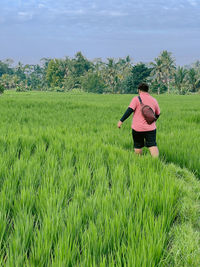 Rear view of woman standing on grassy field