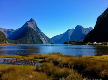Scenic view of lake and mountains against clear blue sky