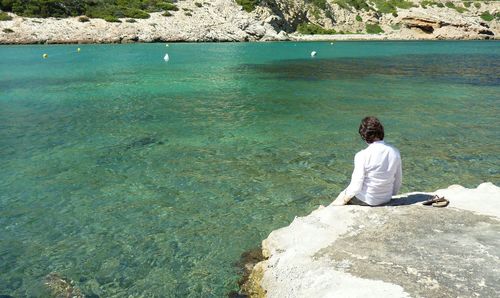 Woman sitting on rock formation by river