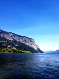 Scenic view of sea and mountains against blue sky