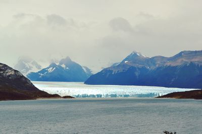 Scenic view of sea and snowcapped mountains against sky