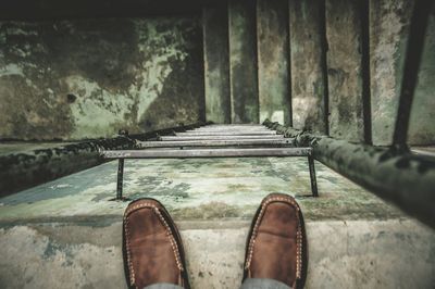 Low section of person standing on wall with ladder