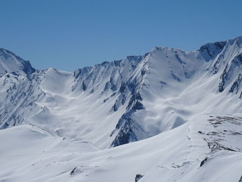 Scenic view of snowcapped mountains against clear blue sky