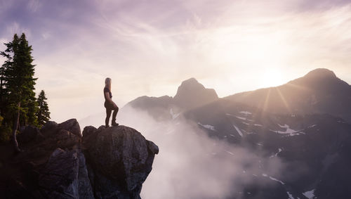 Man standing on rock against sky